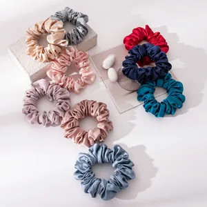 Gedetailleerd overzicht van zijden haarelastieken in diverse kleuren op een wit vlak.