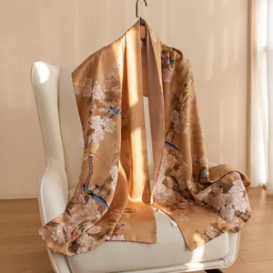 Detail view of elegant gold silk shawl with traditional Chinese floral and bird patterns on chair.