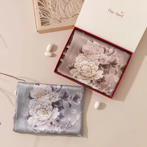 Detailed macro view of luxury mulberry silk scarves featuring elegant peony patterns