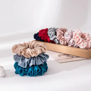 Premium moerbeizijde scrunchies set in diverse kleuren gepresenteerd op een houten dienblad