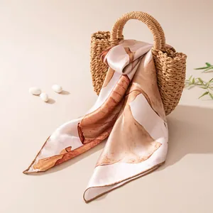 Close-up of lightweight silk square scarf with abstract brown print on a woven bag