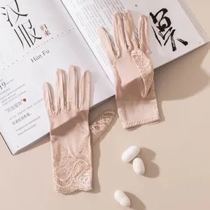 Détail de gants élégants en dentelle chair avec des motifs floraux délicats.
