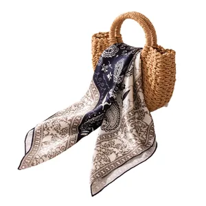 Carré en soie de mûrier élégant avec motif paisley drapé sur un panier en paille tressée