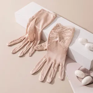 Détail de gants en dentelle beige avec une broderie florale délicate sur le poignet