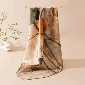 Detail shot of an elegant mulberry silk scarf with floral prints draped on a gold hanger.
