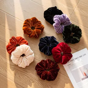 Macro view of various colorful vintage velvet hair scrunchies on a wooden floor.