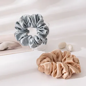 Detail shot of large silk satin scrunchies in blue and gold colors with soft shadows