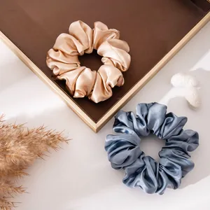 Close-up of elegant silk scrunchies in champagne and blue satin fabric texture.