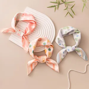 Detail view of three silk scarves with floral patterns and soft pastel colors