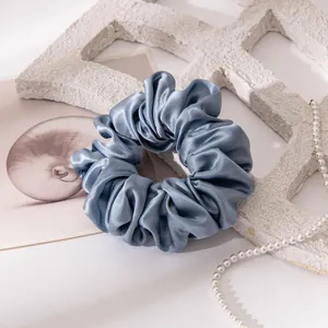 Close-up of a large blue-grey satin silk scrunchie with premium texture detail.