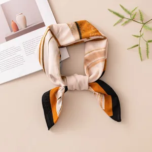 Close-up detail of an elegant silk square scarf featuring abstract geometric patterns