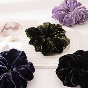 Close-up detail of vintage velvet hair scrunchies in deep green, purple, and navy blue.