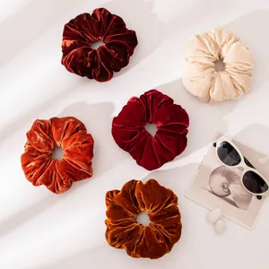Set of five retro velvet scrunchies in warm autumn tones on a minimalist white background