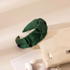 Close-up detail of a dark green handmade silk knotted headband with elegant jacquard texture