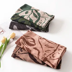 Folded retro floral silk scarves with artistic leaf print displayed with yellow tulips