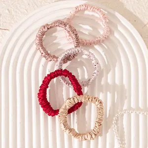 Elegant 100% mulberry silk scrunchies in various colors on a textured white decorative tray.