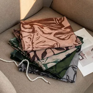 Close-up detail of luxury vintage leaf print scarves stacked on a neutral sofa.