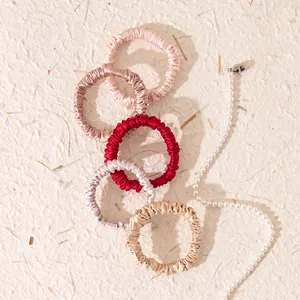 Detail view of multicolored small 1cm mulberry silk hair scrunchies on textured background