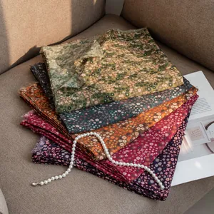 Close-up of stacked vintage floral scarves showing various colors and soft texture