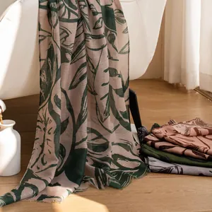 Detailed view of vintage leaf-printed lightweight shawl draped over a minimalist white chair