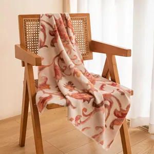 Elegant pink floral printed long scarf shawl draped over a vintage wicker armchair