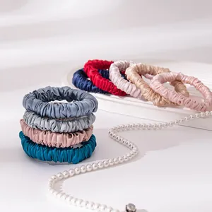Premium silk satin scrunchies in assorted colors arranged with an elegant pearl necklace