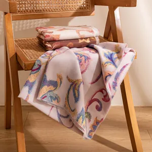 Elegant pink long scarf with floral paisley print draped over a rustic vintage wooden chair