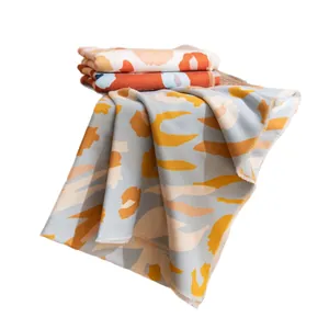 Chal suave de tacto cachemira con estampado abstracto naranja y azul sobre blanco.