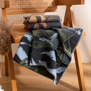 Elegant wool blend scarf with abstract patterns draped on a rustic wooden chair.