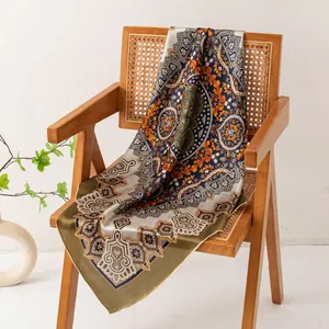Close-up of elegant vintage paisley print silk scarf draped on a wooden rattan chair.