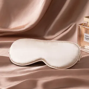 Détail du masque de sommeil en soie champagne montrant une texture satinée élégante
