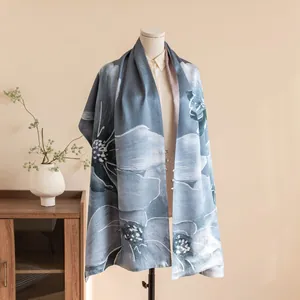 Detailed display of a luxury blue floral silk shawl draped on a neutral mannequin stand.