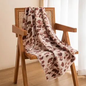 Elegant brown leopard print winter shawl draped on a rattan chair in a cozy warm room setting