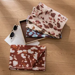 Set of stylish leopard print winter scarves in earthy tones on a rustic wooden floor
