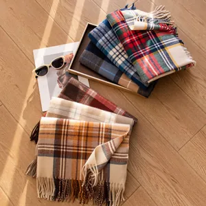 Assorted colorful plaid scarves with decorative tassels on a rustic wooden floor
