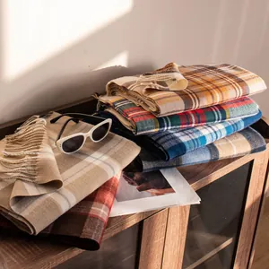 Various soft plaid imitation cashmere scarves folded on a wooden cabinet detail