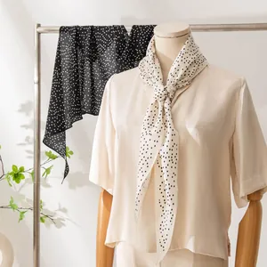 Elegant polka dot silk scarf for women displayed on a mannequin and clothing rack