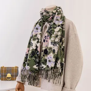 Detailopname van een elegante sjaal met bloemenprint en franjes op een beige paspop.
