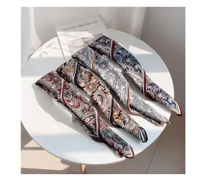 Detailed view of four elegant wool scarves with colorful paisley prints arranged on a round table.