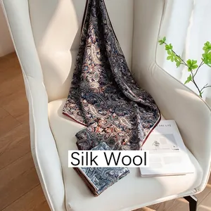 Elegant navy blue paisley print silk wool scarf for women displayed on a white chair