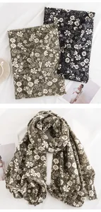 Detail view of floral daisy print tassel scarf in olive green and black for winter