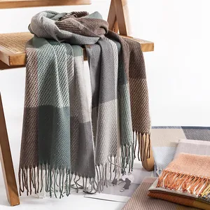 Warm cashmere-like plaid scarf with elegant long tassels draped over a wooden chair