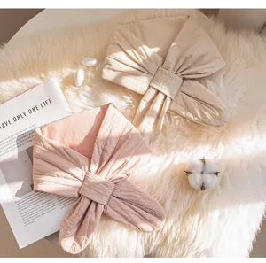Two padded silk-filled triangular scarves in pink and beige on a white fur background