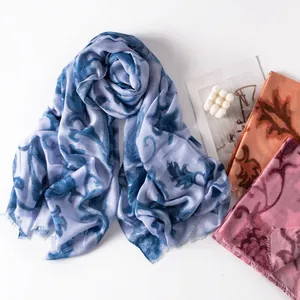 Macro detail of lightweight floral printed scarves in elegant blue, orange and pink tones