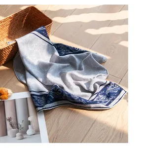 Élégant foulard en soie et laine bleue à motif cachemire sur sol en bois clair au soleil