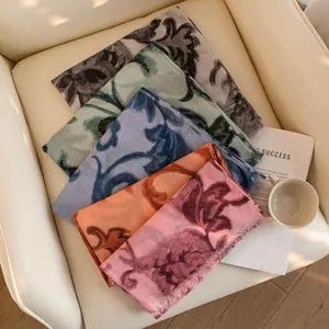 Detailed display shot of various artistic printed oversized scarves and shawls on a chair