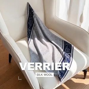 Écharpe élégante en soie et laine à imprimé bleu porcelaine sur un fauteuil blanc