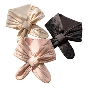 Set of three silk-filled winter neck warmers in beige, black, and pink with bow design.