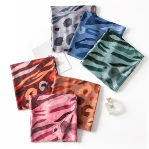 Group of colorful thin silk scarves with ethnic animal prints arranged on white background