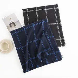 Close-up detail of two stylish checkered scarves with fringe edges in black and navy blue